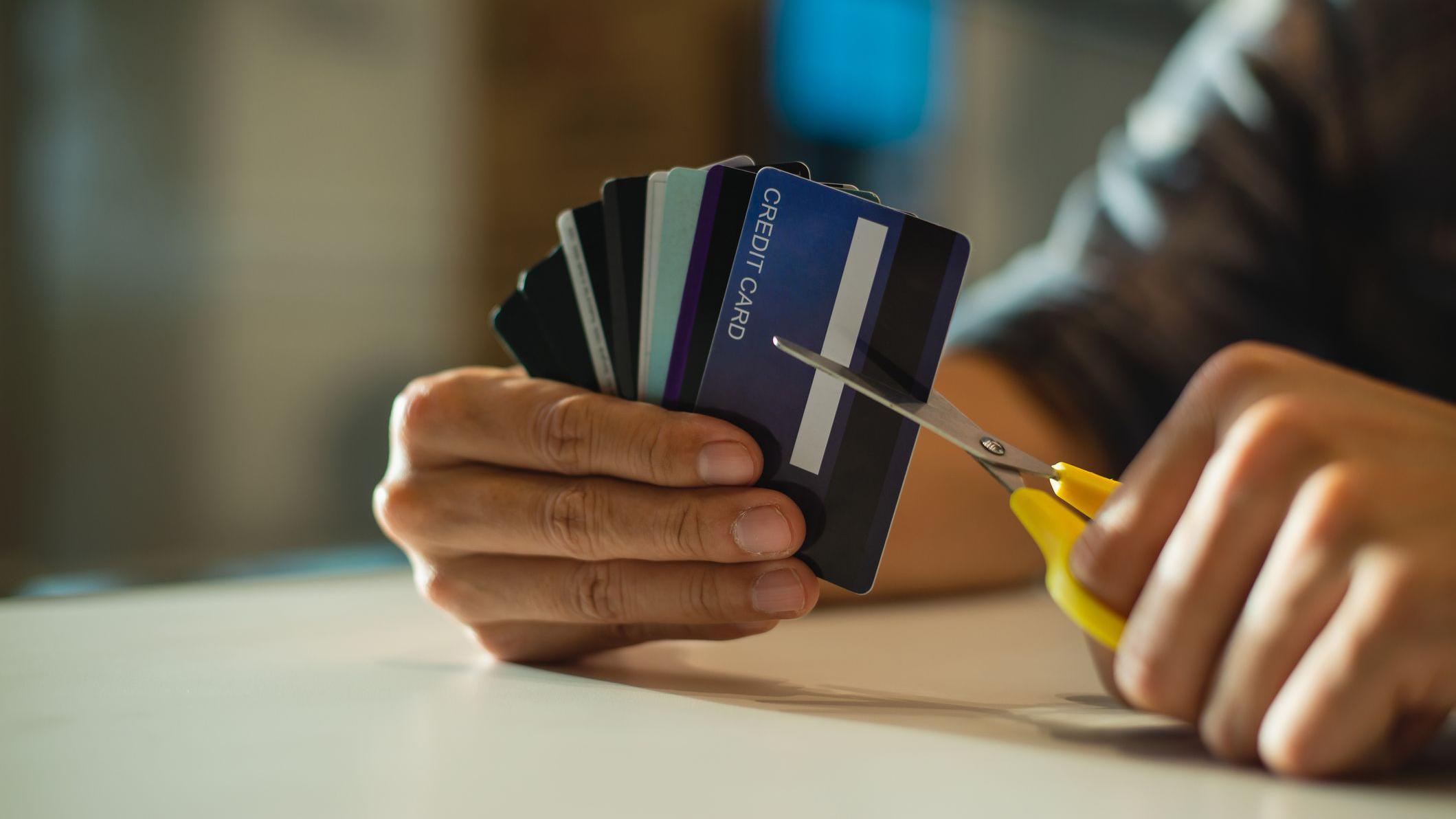 Una persona corta una tarjeta de crédito con una tijera.