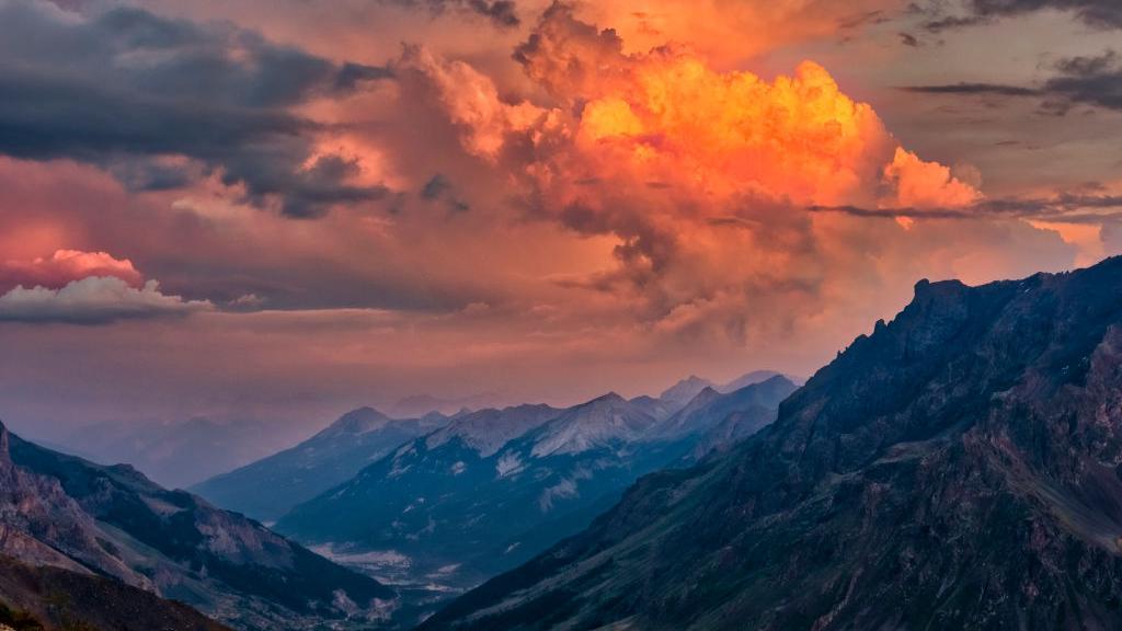 Lanskap pegunungan Dauphine Alps Prancis di kejauhan, terlihat dari celah Col du Galibier saat matahari terbenam.