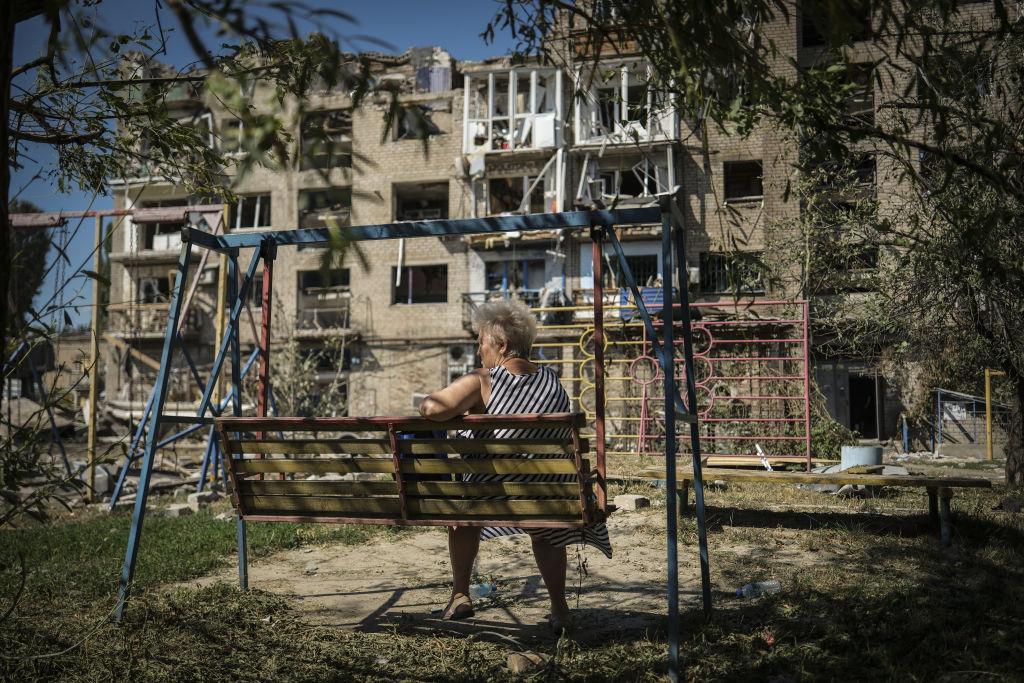 Una mujer sentada frente a un edificio dañado por un ataque con misiles rusos.