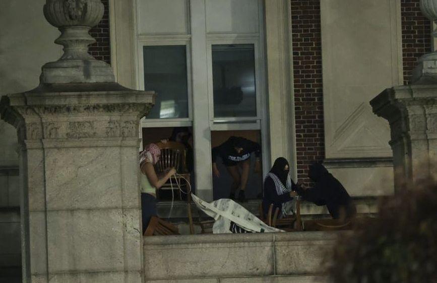 Activistas salen por las ventanas del edificio para colgar un cartel.