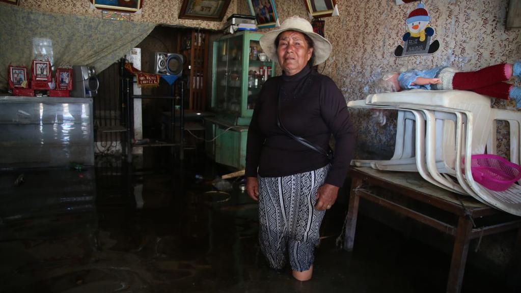 Una mujer en Perú con su casa inundada por lluvias relacionadas con el Fenómeno del Niño