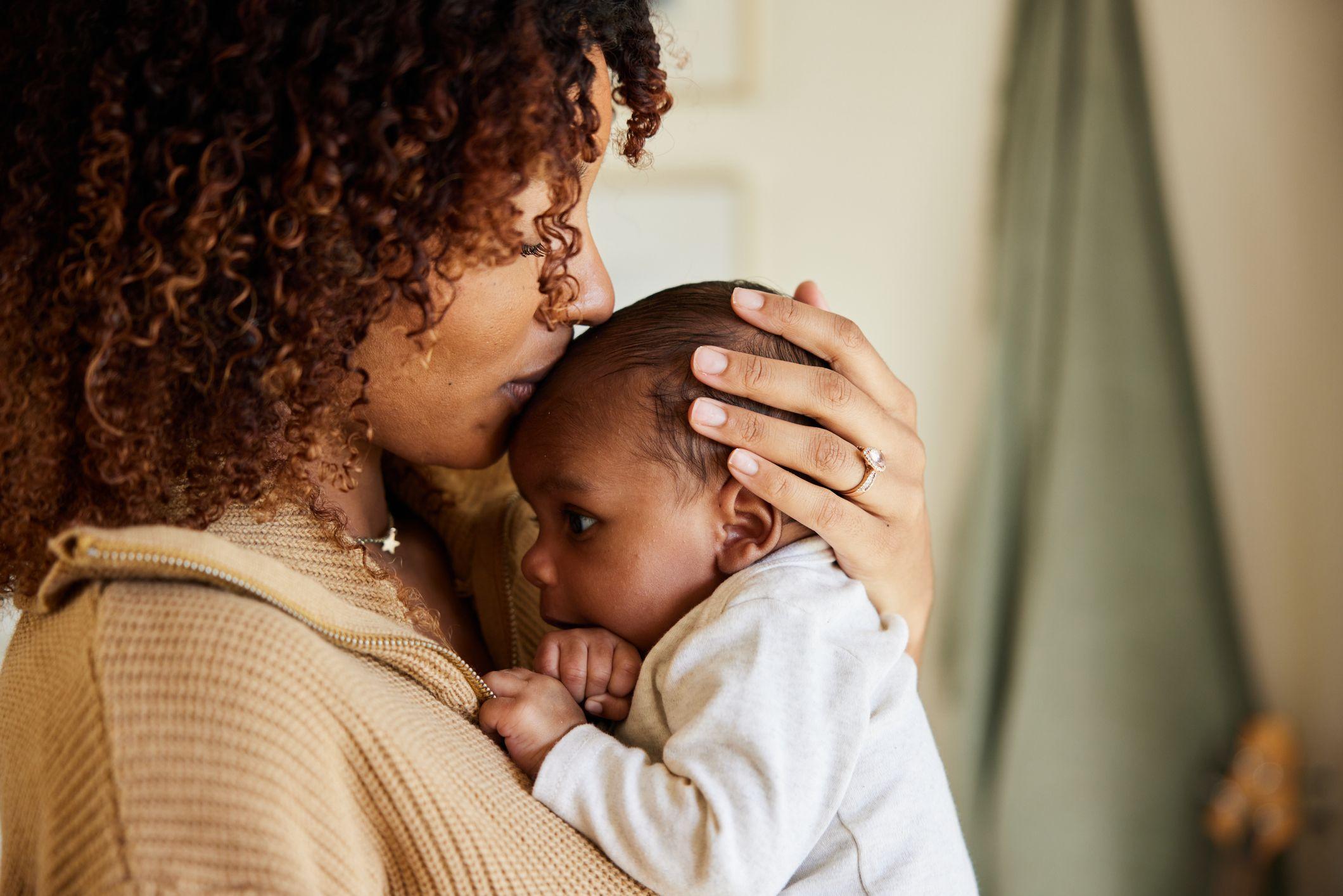 Mulher com bebê no colo, beijando-o na testa