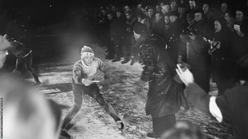 Um competidor na corrida de 1963 chega à cidade de Sneek, segurando o cartão que precisa carimbar para provar que passou em todos os pontos de controle do percurso