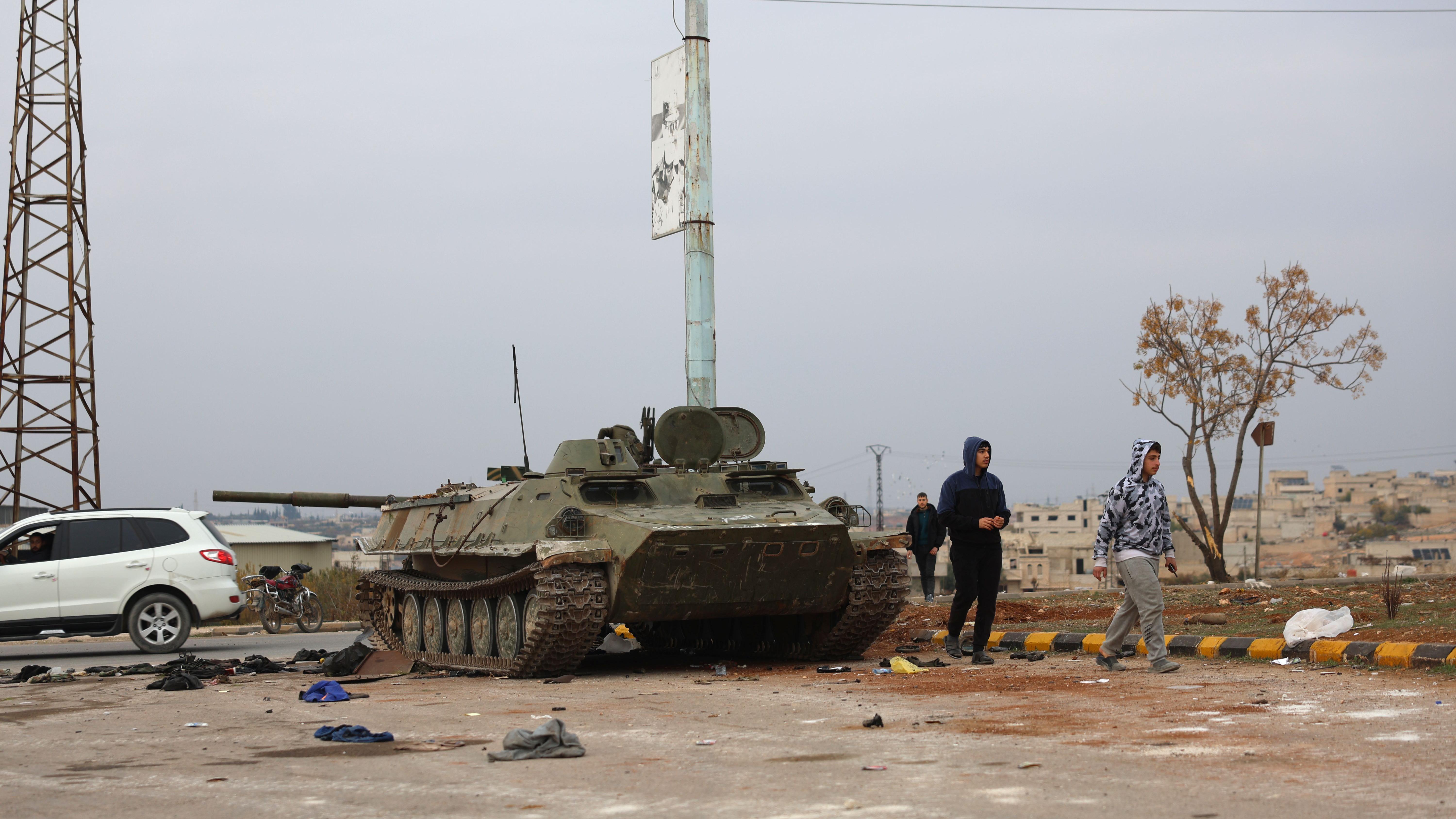 Pessoas passam por um tanque abandonado pelas tropas sírias depois que os combatentes da oposição assumiram o controle da cidade de Hama, na Síria, em 07 de dezembro de 2024. 