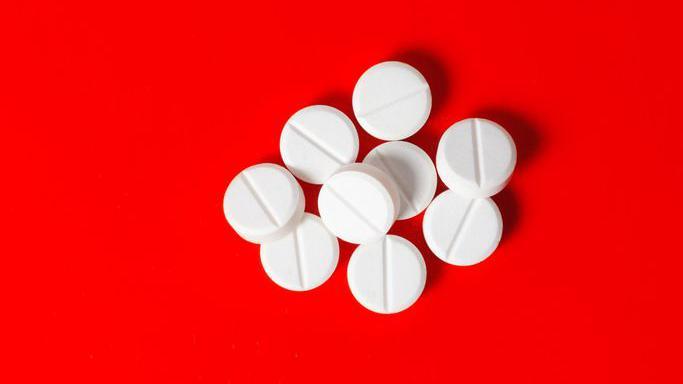 Comprimidos brancos num fundo vermelho