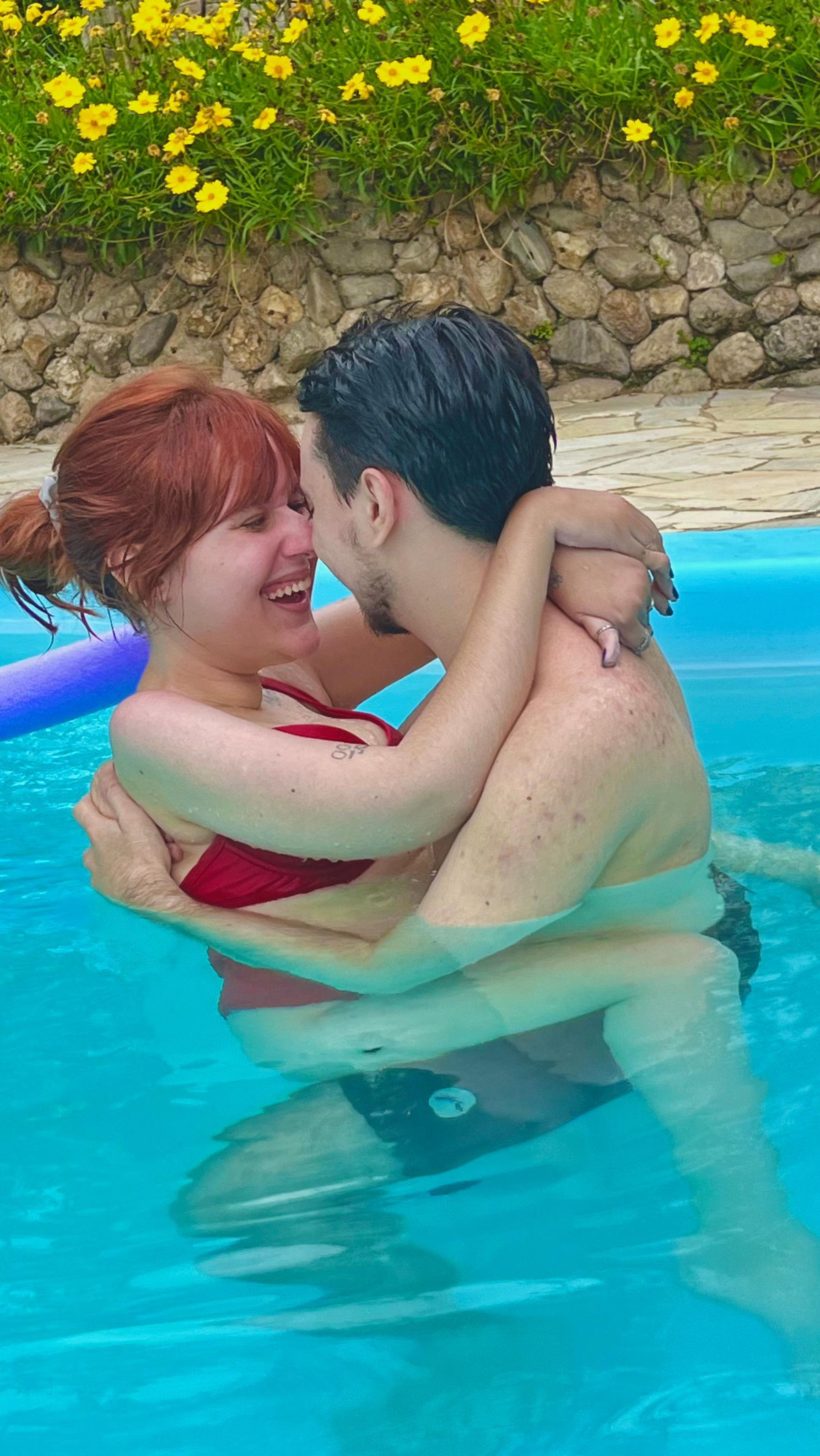 Marina e Victor abraçados enquanto sorriem em foto dentro da piscina