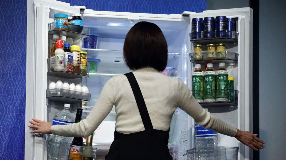 Un mujer abre un refrigerador ordenado