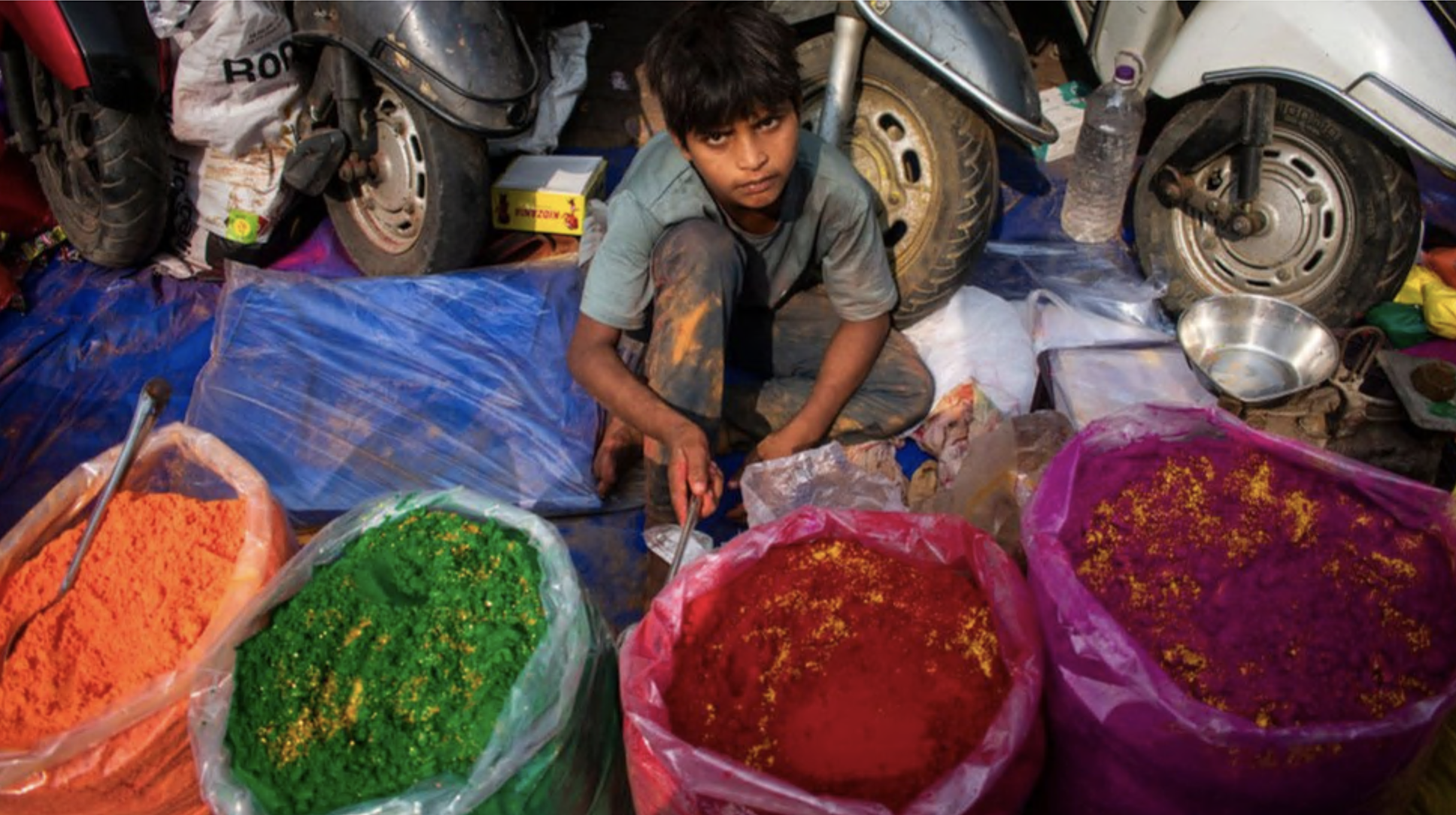 A boy selling coloured powder or Gulal at a market