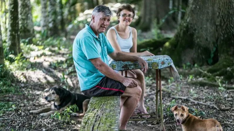 Homem e mulher sentados em floresta com cachorro