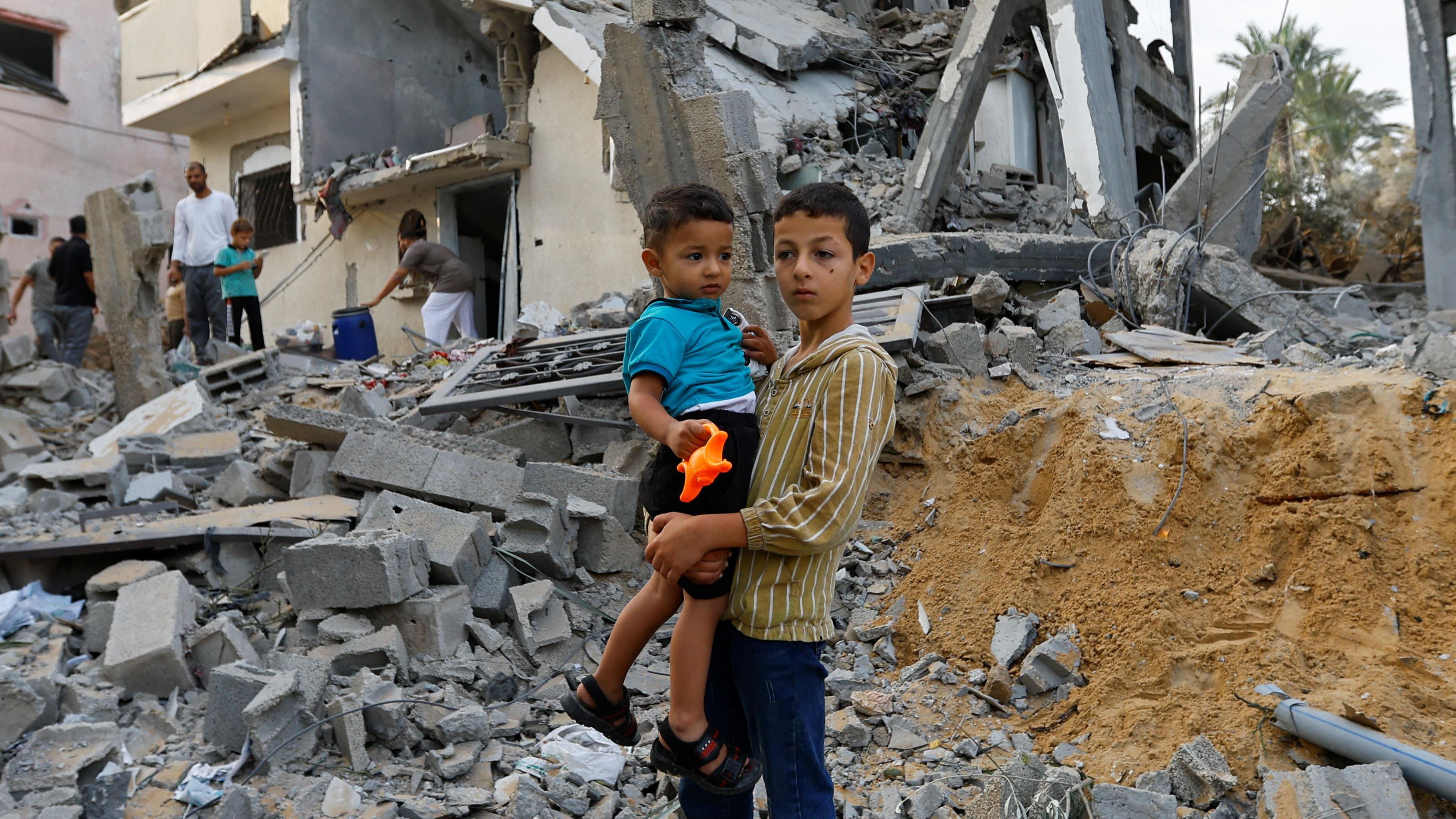 Dos niños parados sobre los escombros.
