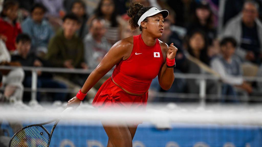 Naomi Osaka na quadra de tênis com uma raquete na mão