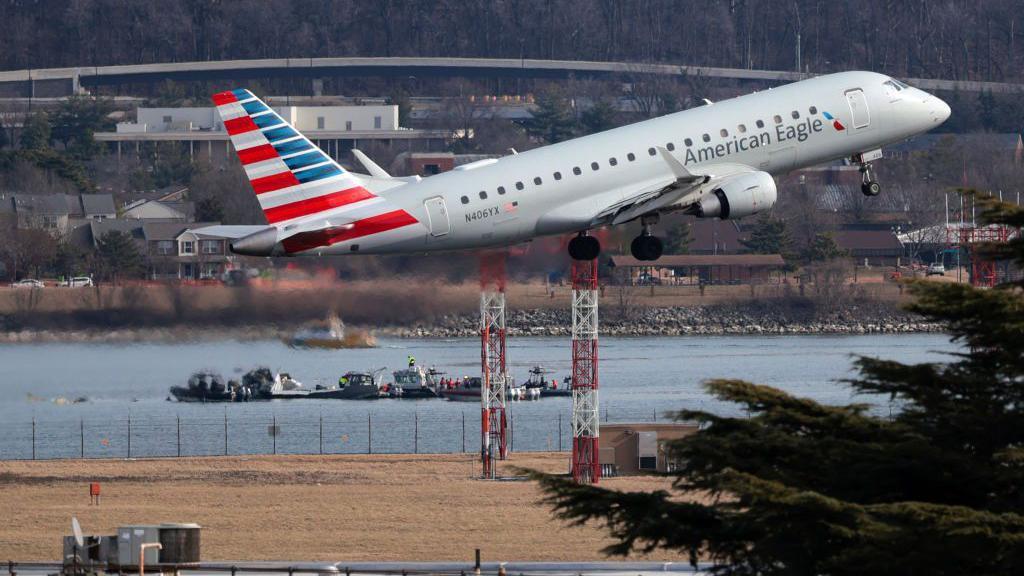 Un avión despega en el aeropuerto Ronald Reagan mientras equipos de rescate trabajan en el río Potomac