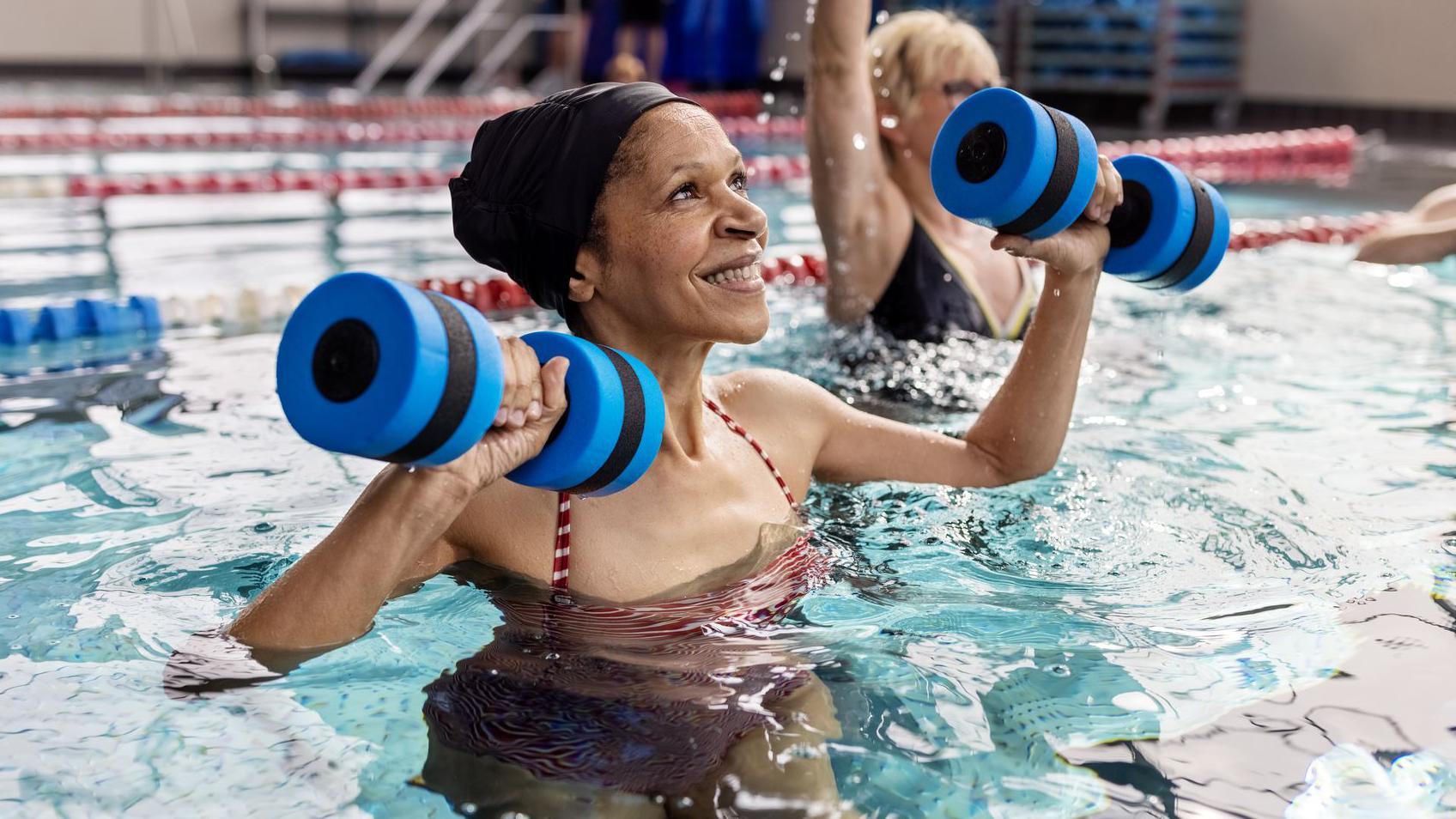 Mulher idosa levantando pesos em uma piscina