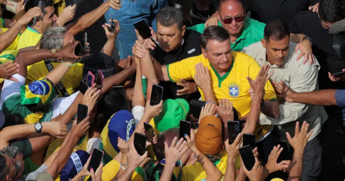 Jair Bolsonaro usando camisa amarela da seleção durante um evento em que está cercado de apoiadores