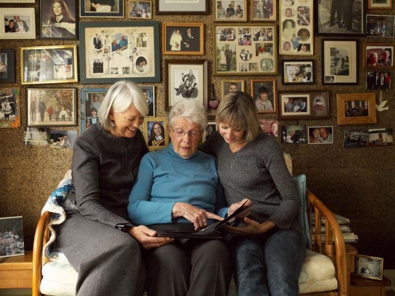 Mulheres de três gerações diferentes vendo álbum de fotos juntas