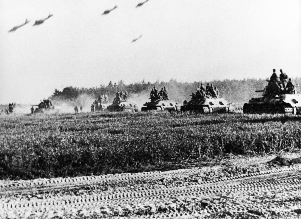 imagem histórica em preto e branco mostra sequencia de tanques avançando sob campo