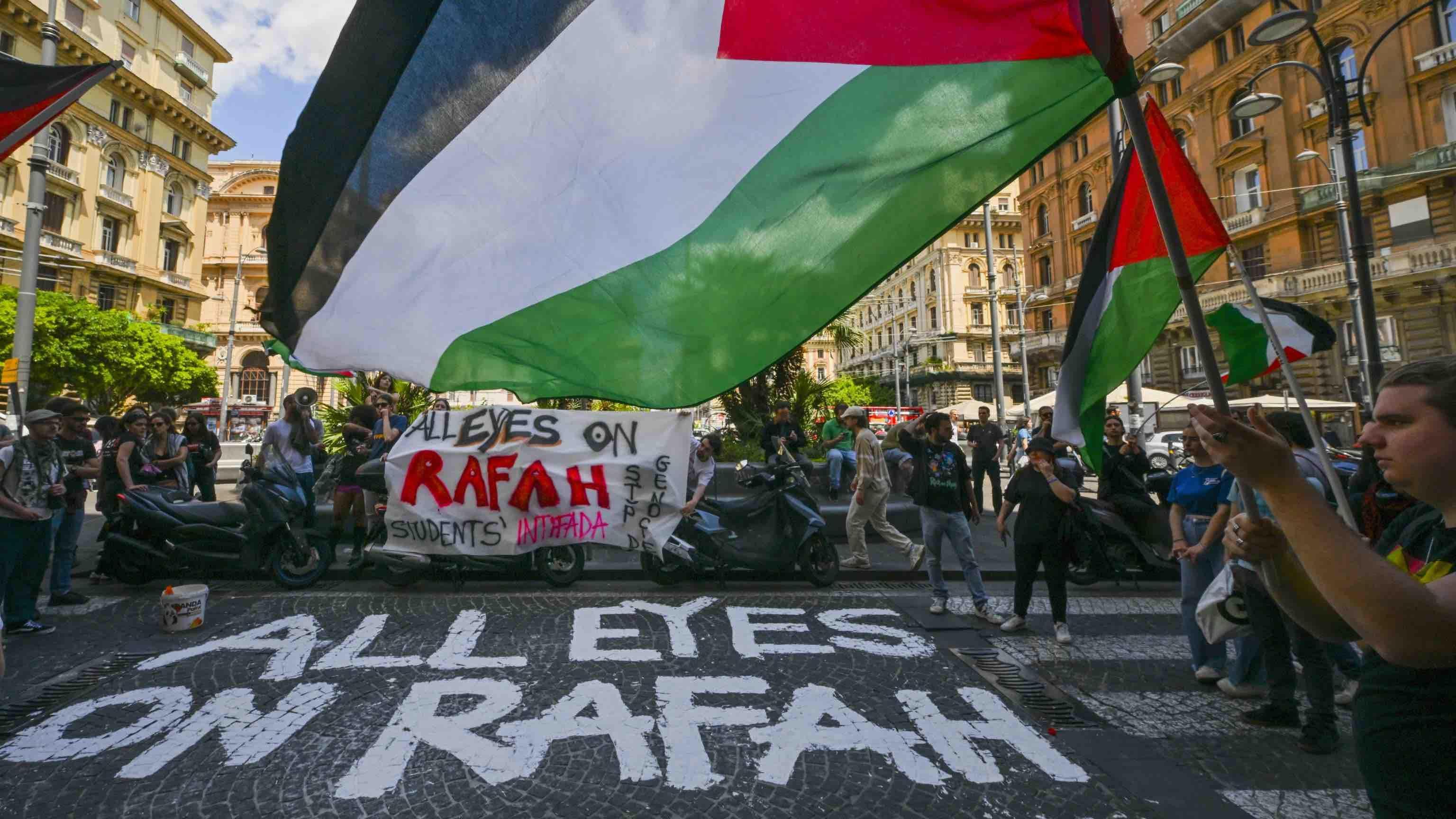 Estudiantes propalestinos en Nápoles protestan frente a una empresa de logística israelí, con la frase "Todos los ojos puestos en Rafah" pintada en el suelo.
