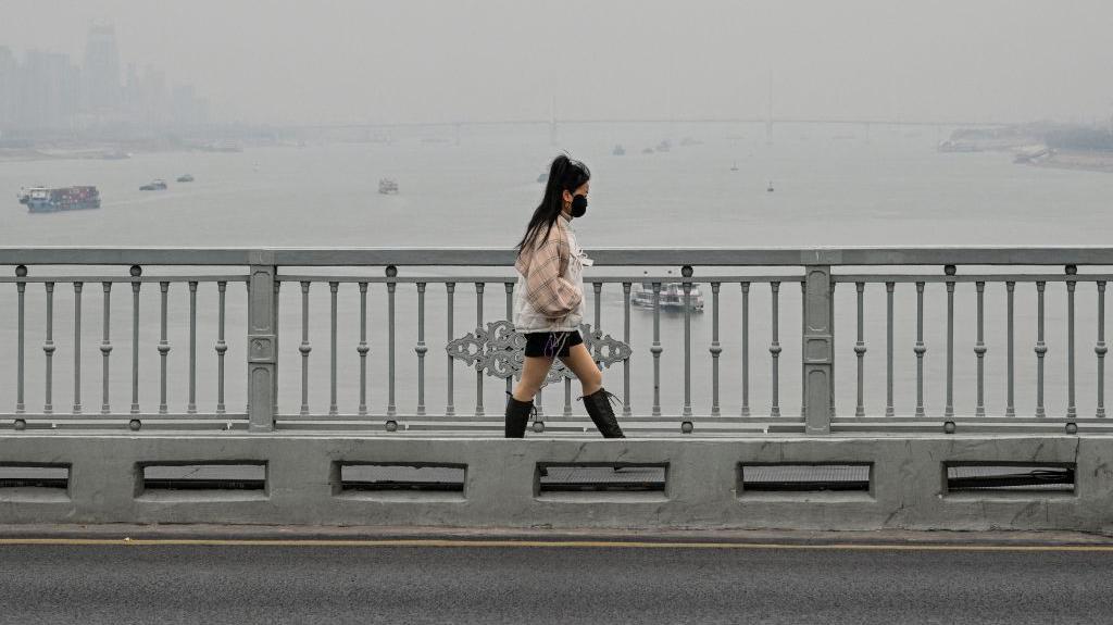 Uma mulher caminha na ponte sobre o rio Yangtze em Wuhan, província de Hubei, centro da China, em 22 de dezembro de 2024.