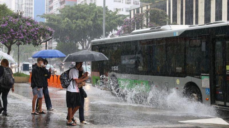 Pessoas com guarda-chuvas sob forte chuva