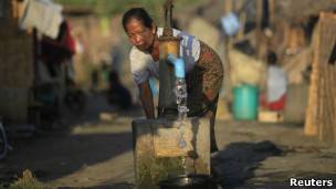 Mulher coleta Ã¡gua no Mianmar. | Foto: Reuters