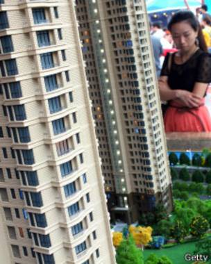 Mujer china frente a maqueta de vivienda.