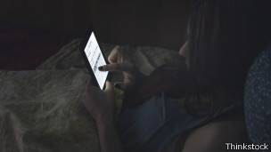 Mujer leyendo un libro electrónico en la oscuridad