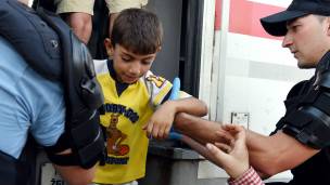la policía croata ayuda a un niño migrante a bajarse de un tren