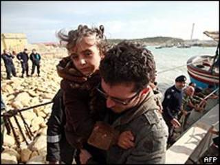 Imigrante leva filha ao desembarcar de barco de pesca em Malta, vindo da África