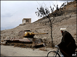 مرد افغان در حال عبور از کنار لاشه یک تانک