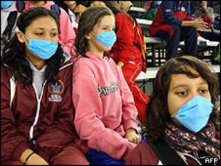 Mexicanos vistiendo máscaras para evitar brote de gripe porcina.