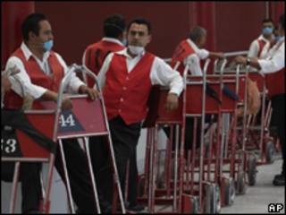 Carregadores de malas usando máscaras aguardam passageiros em rodoviária mexicana (AP)