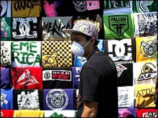 Mexicano com máscara passa por camisetas à venda na Cidade do México