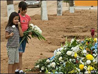 Niñas ponen flores durante el funeral por los fallecidos en guardería de Sonora