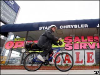 Ciclista pasa delante de concesionaria de Chrysler en venta