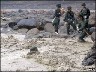 Foto liberada pelo governo de Taiwan mostra militares cruzando rio ao realizarem buscas na vila de Shiao Lin (AFP, 11 de agosto)