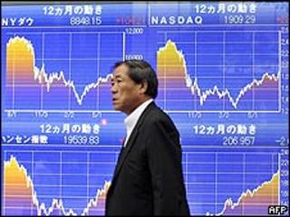 Japonés pasea junto a pantallas con datos bursátiles. Archivo.