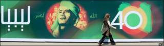 Mujer pasa frente a valla conmemorativa en Libia