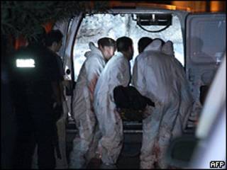 Personal forense coloca el cuerpo de un ejecutado en ambulancia en Ciudad Juárez.