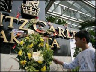 طفل يضع زهور أمام فندق ريتز كارلتون حيث وقعت تفجيرات يوليو