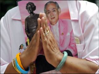 Một phụ nữ Thái Lan mang theo chân dung của Vua Bhumibol Adulyadej khi cầu nguyện cho Vua