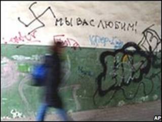 Женщина идет мимо стены с расистскими надписями на русском языке