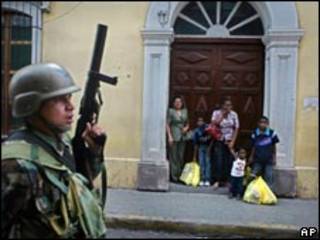 Soldado é observado por hondurenhos em rua de Tegucigalpa na última quarta-feira (AP)