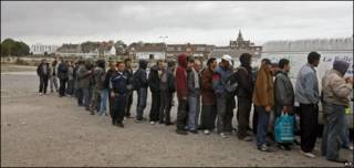 Inmigrantes en Calais, Francia, esperan por la comida de una organización benéfica