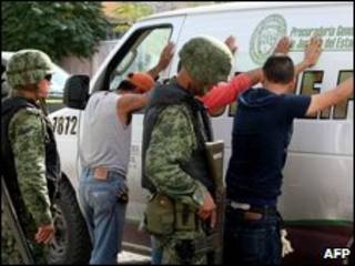 Soldados mexicanos revistam suspeitos perto de uma cena de assassinato em Ciudad Juarez