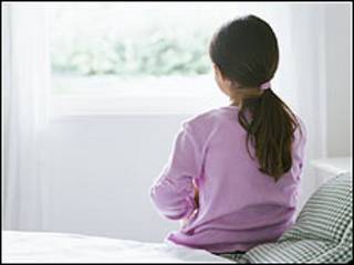 Niña sentada en una cama observa la ventana (Foto: Archivo)