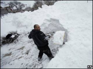 Homem retira neve de calçada na cidade de Des Moines, Iowa, nesta sexta-feira (AP)