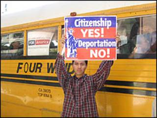 Joven inmigrante sostiene un cartel alusivo.