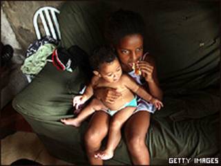 Menina segura bebê no colo em favela no Rio de Janeiro