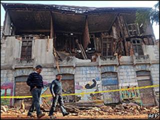 Moradores de Valparaiso, Chile, passam em frente a prédio destruído