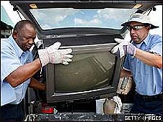 Dos hombres transportan un viejo televisor.
